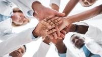 Medical team members bring hands in together.